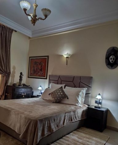 Chambre élégante avec un lit, des lampes de chevet et des décorations murales.