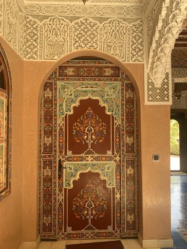 Porte ornée de motifs colorés et arabesques dans un décor traditionnel.