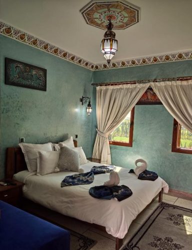 Chambre décorée avec un lit double, des rideaux clairs et des éléments traditionnels.