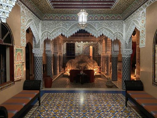Intérieur d'un palais marocain avec des arches décorées et un éclairage chaleureux.